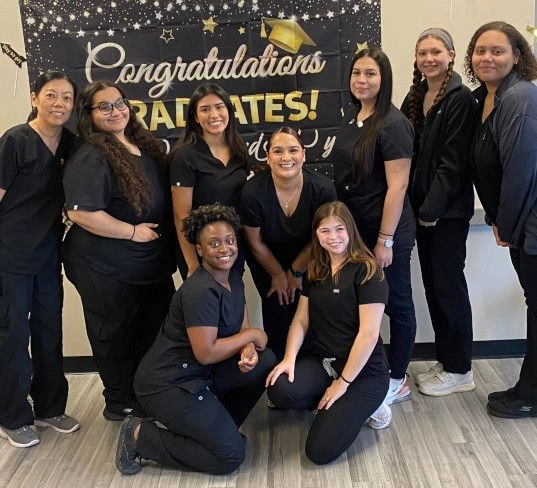 graduates standing in front of congratulatory banner graduates standing in front of congratulatory banner
